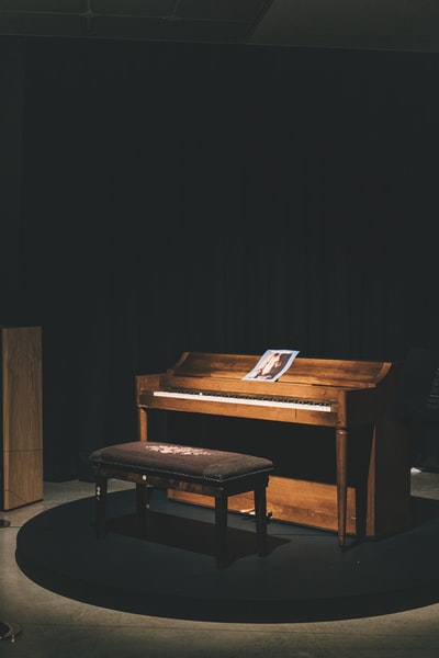 棕色的木质直立式钢琴与奥斯曼板凳和兴奋的光
